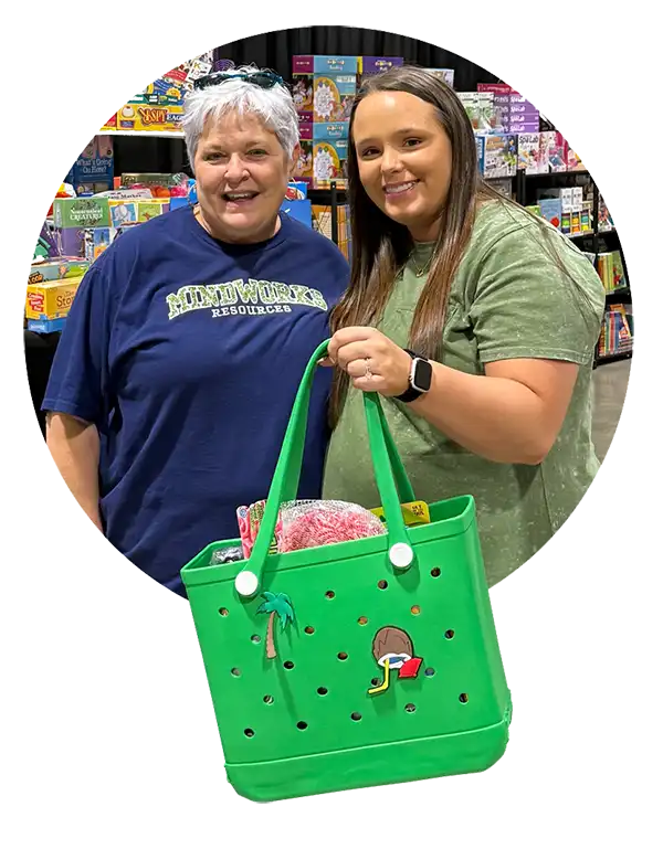 Lisa from MindWorks poses with the raffle winner, who’s holding a green prize tote, in front of the MindWorks booth.